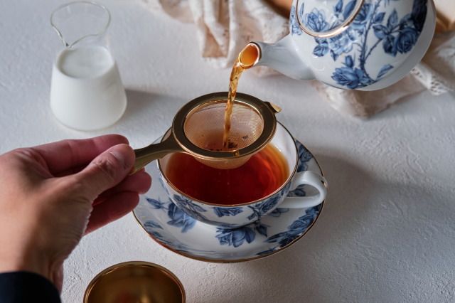 ストレートティーの濃さの紅茶。茶葉をティーポットに残して提供。ミルクを添える方法